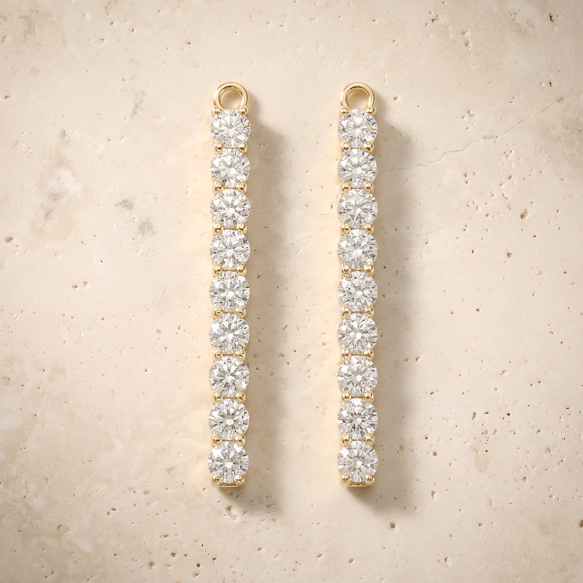 Earrings in 14K solid gold, slim nine-stone diamond bar drops on cream travertine