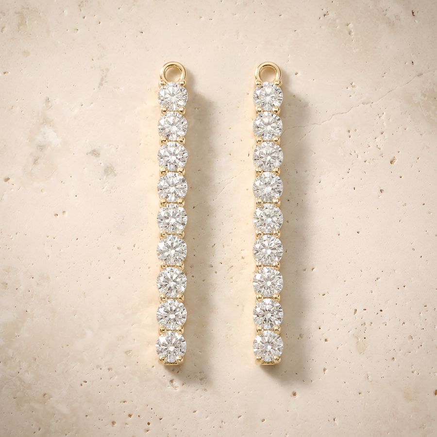 Earrings in 14K solid gold, slim nine-stone diamond bar drops on cream travertine